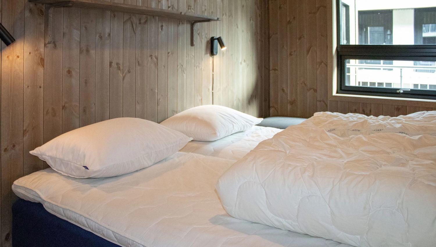 A bed with pillows and a lamp in a room.