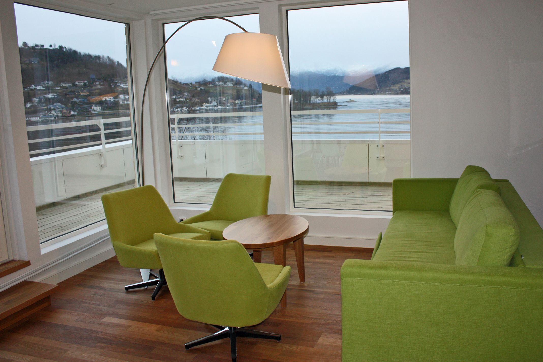Moderne lounge på Thon Hotel Sandven med stilige grøne møblar og fantastisk utsikt over Hardangerfjorden.