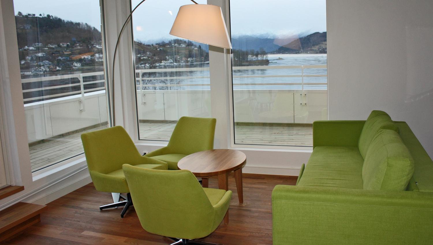 Moderne lounge på Thon Hotel Sandven med stilige grøne møblar og fantastisk utsikt over Hardangerfjorden.