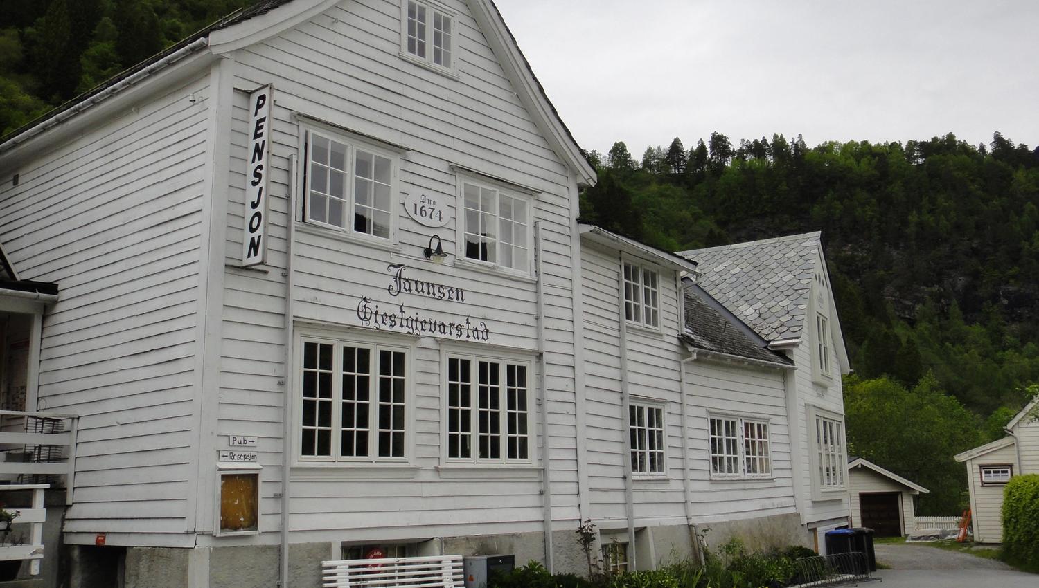 The historic exterior of Jaunsen Guesthouse from 1674, surrounded by beautiful Hardanger nature.