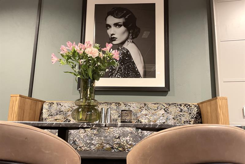 Detail photo of a black and white photography, seating section and a flower in a vase.