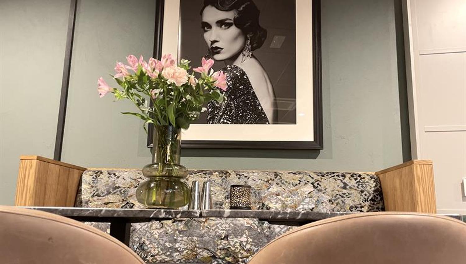 Detail photo of a black and white photography, seating section and a flower in a vase.
