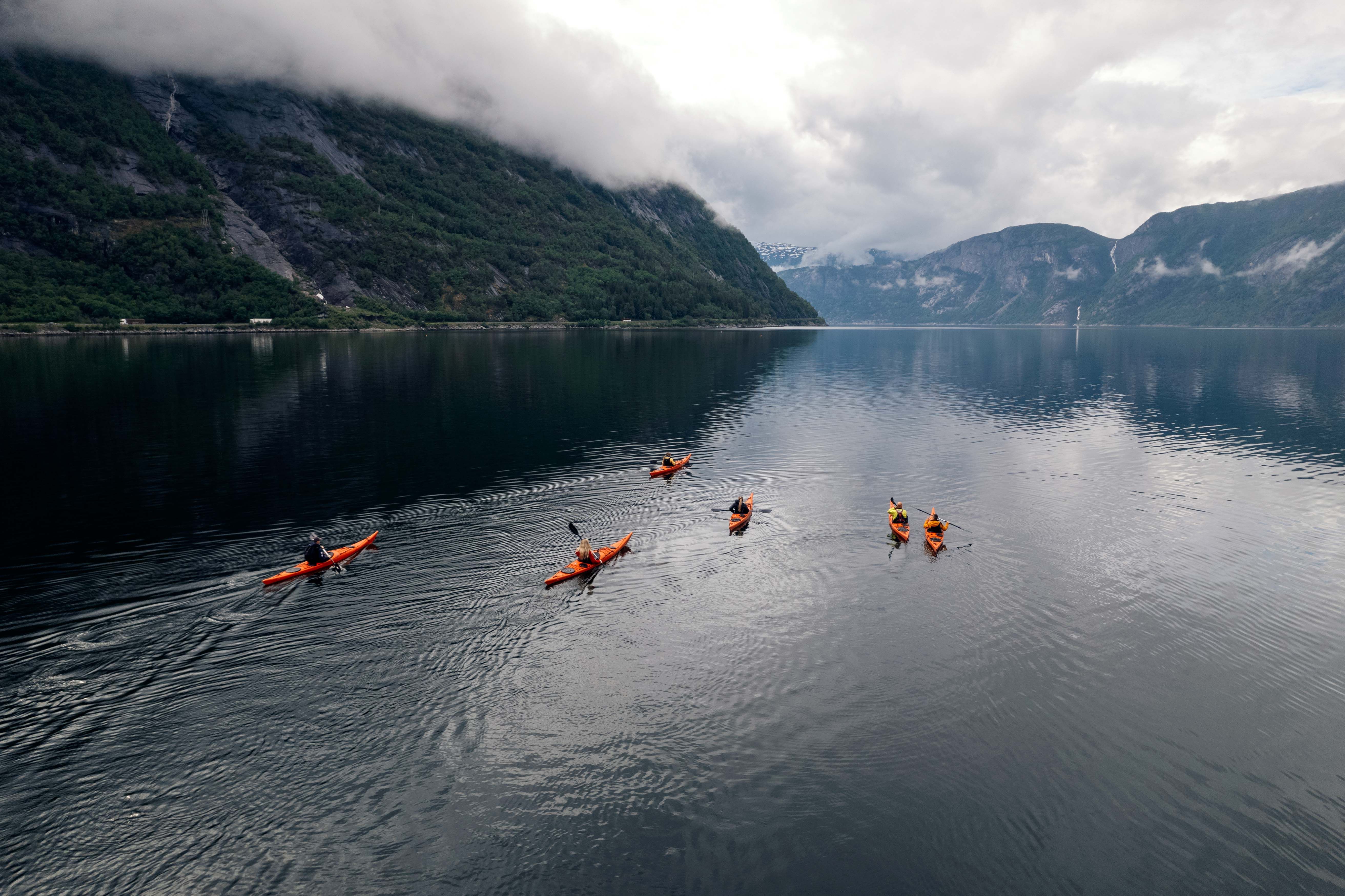 A drone photo of several kayakers paddling on the fjord.