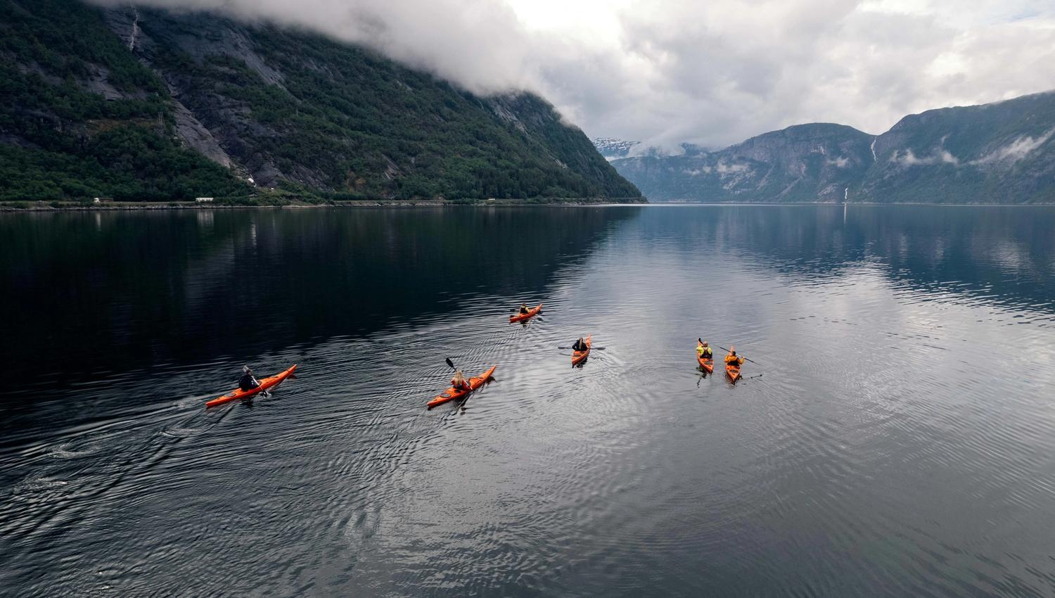 A drone photo of several kayakers paddling on the fjord.