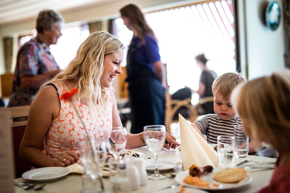 mor og barn sitter på restaurant på Straand Hotel
