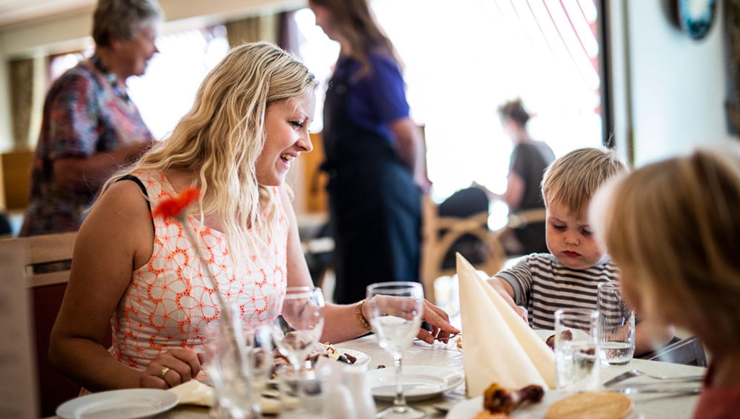 mor og barn sitter på restaurant på Straand Hotel