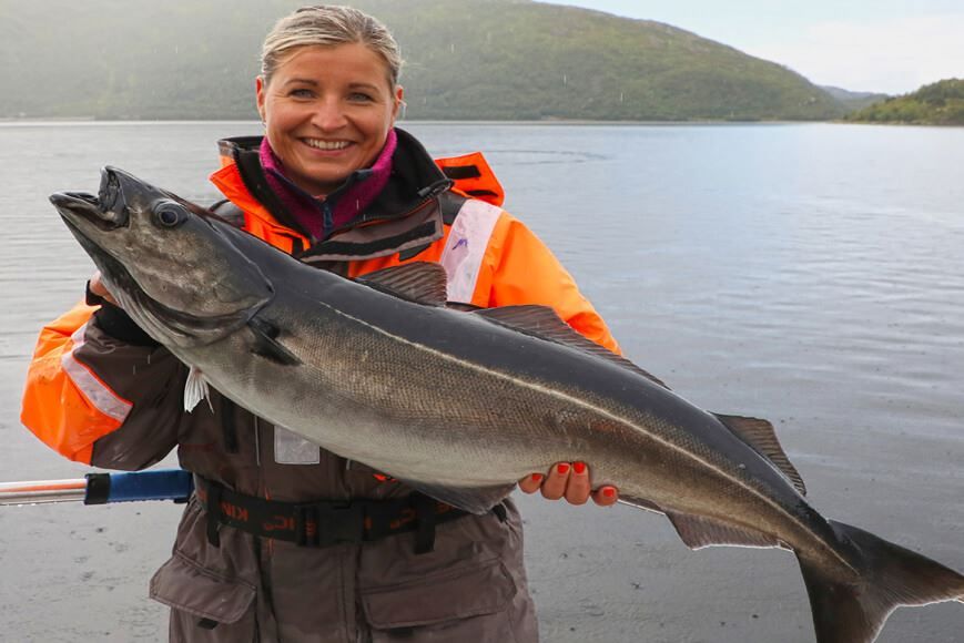 Woman holding a fish on a fishing trip with Explore the Arctic