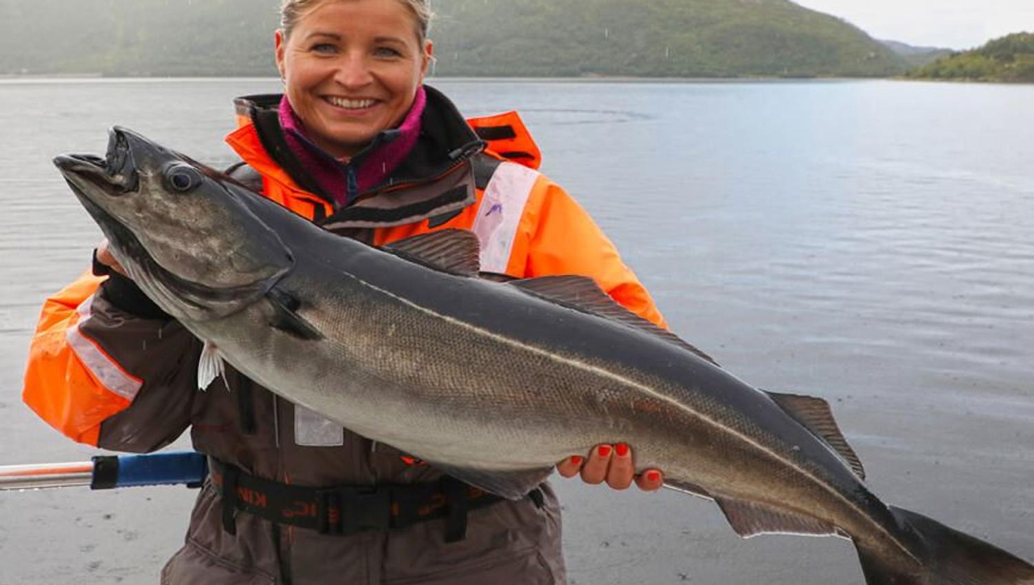 Woman holding a fish on a fishing trip with Explore the Arctic