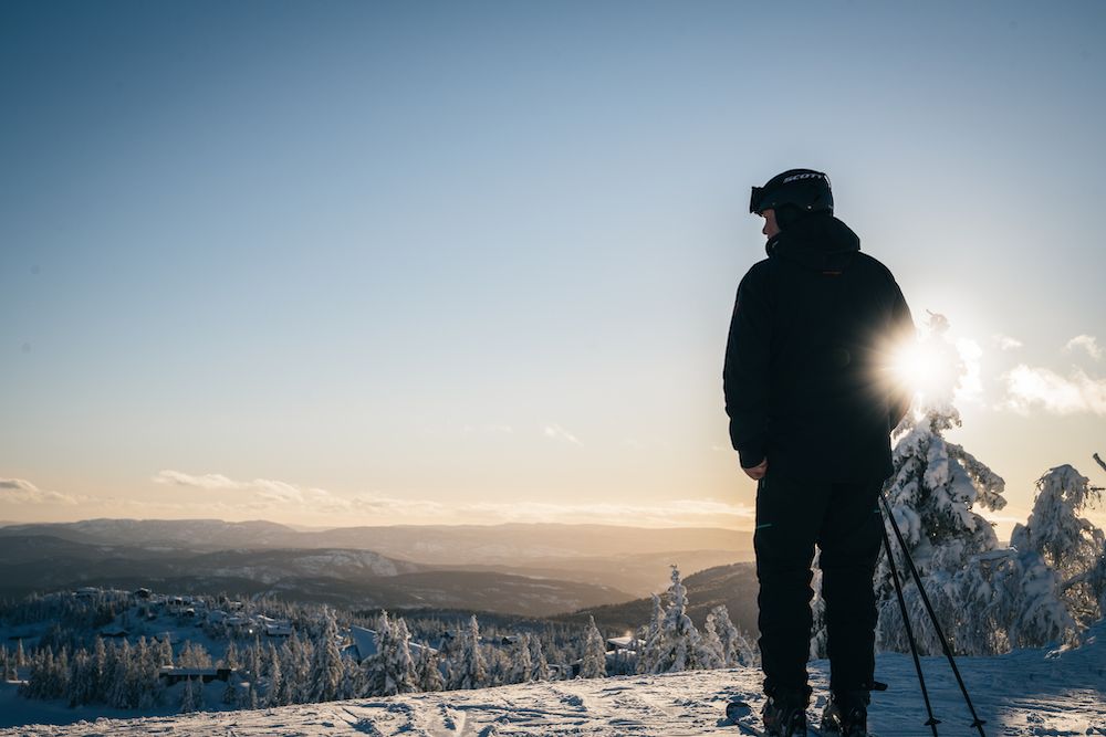 mann på ski står på en top på Lifjell skisenter og ser ut over landskapet