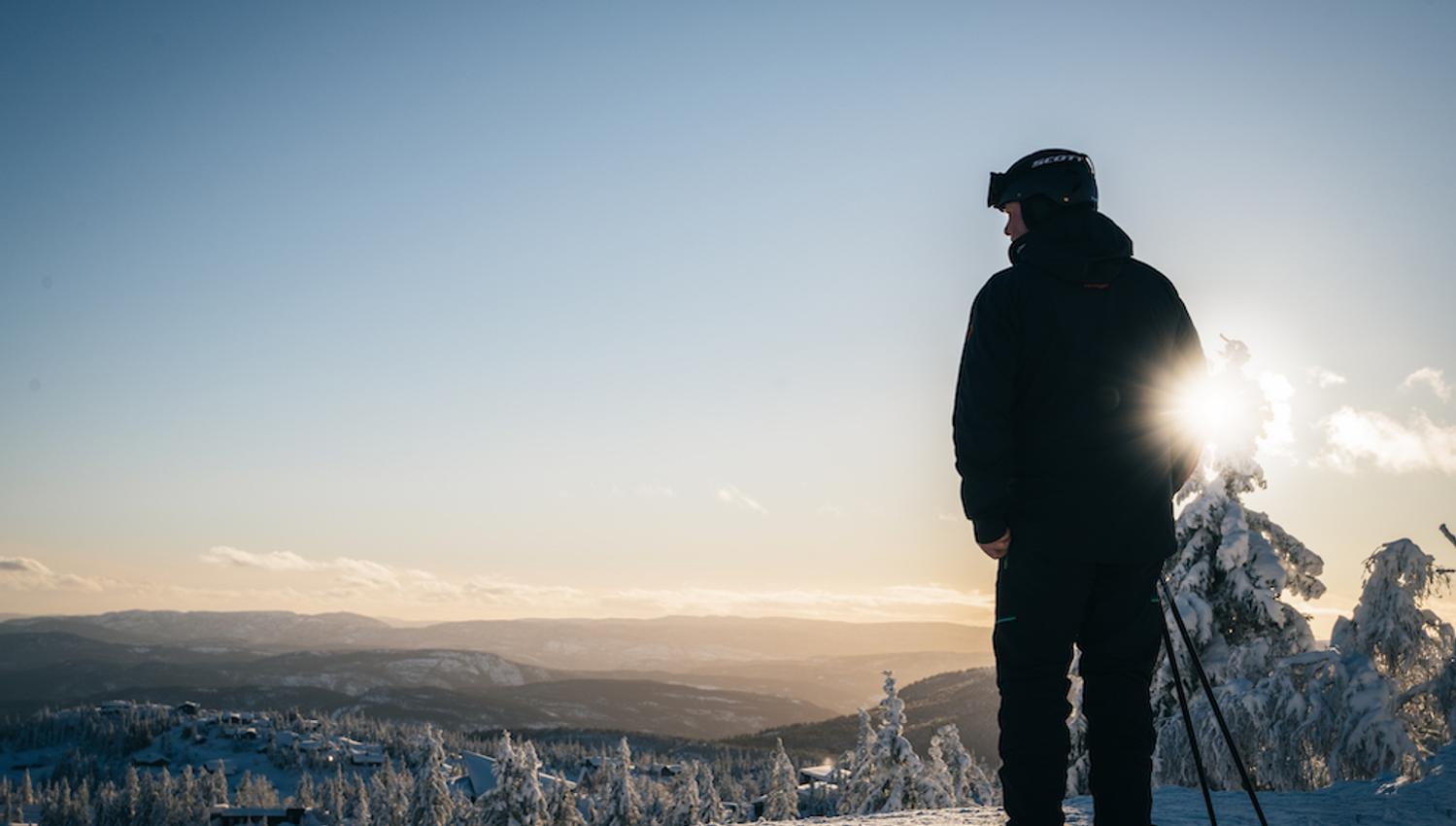 mann på ski står på en top på Lifjell skisenter og ser ut over landskapet