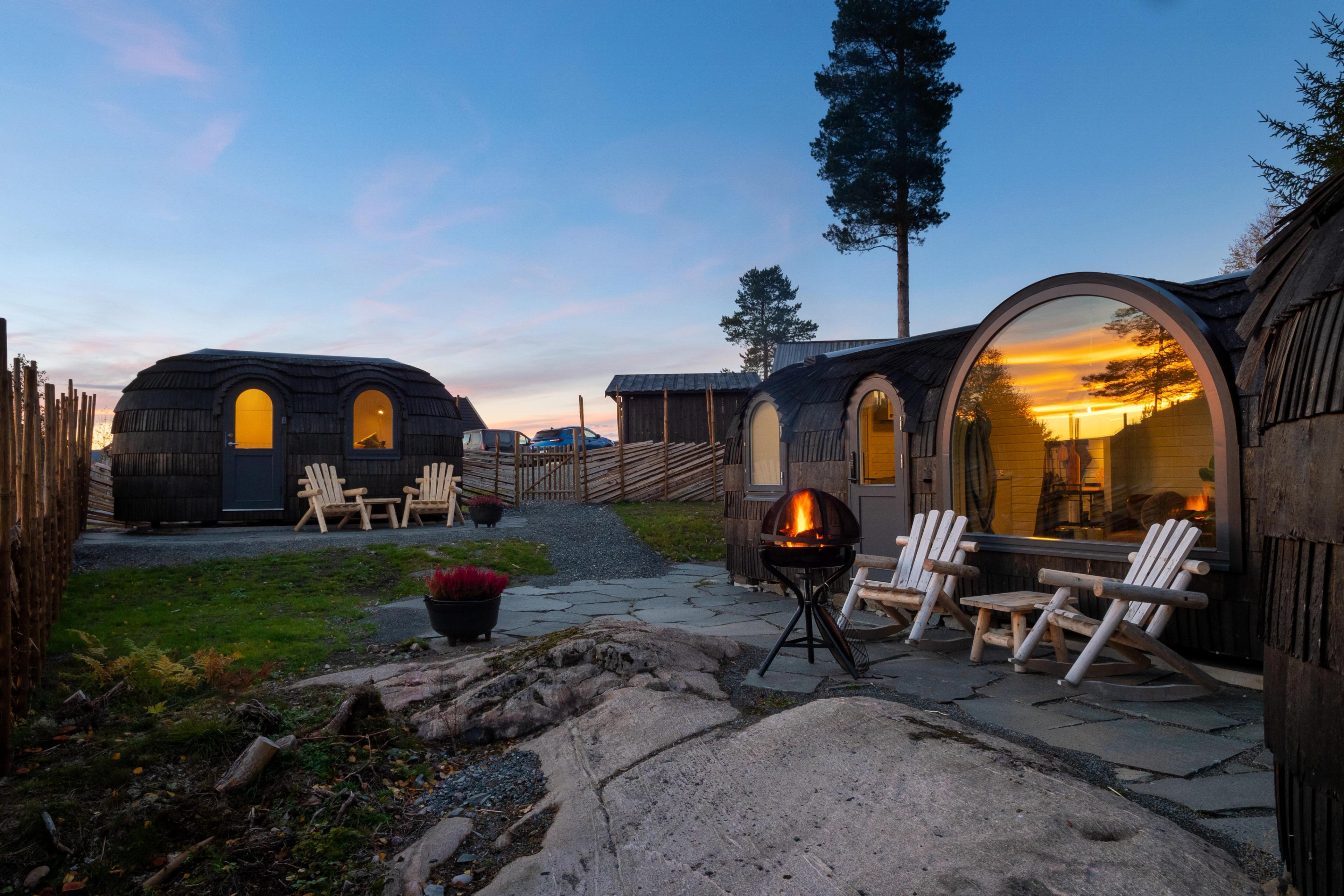 Three small cabins with large windows and chairs in front.