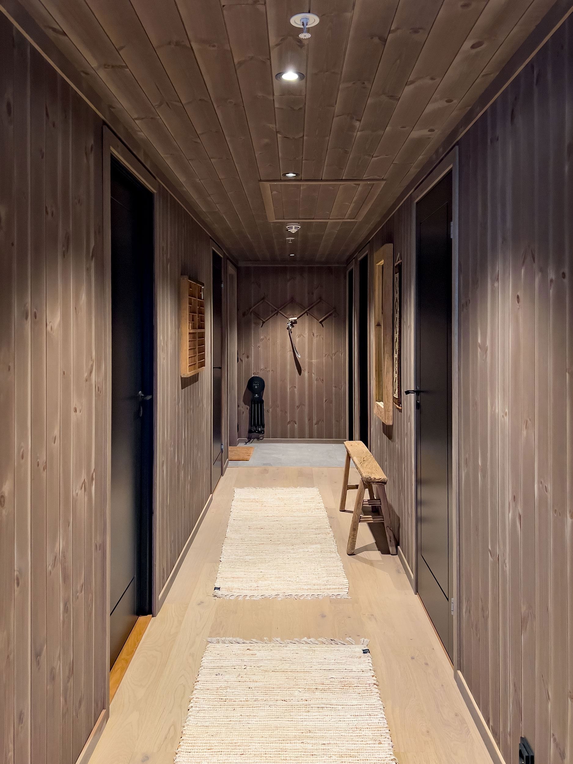 A corridor with a wall of wood paneling and a wooden bench.