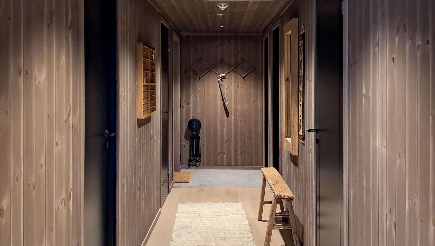 A corridor with a wall of wood paneling and a wooden bench.
