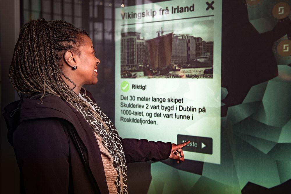 Besøkande brukar informasjonsskjerm for å lære meir om vikingtida.