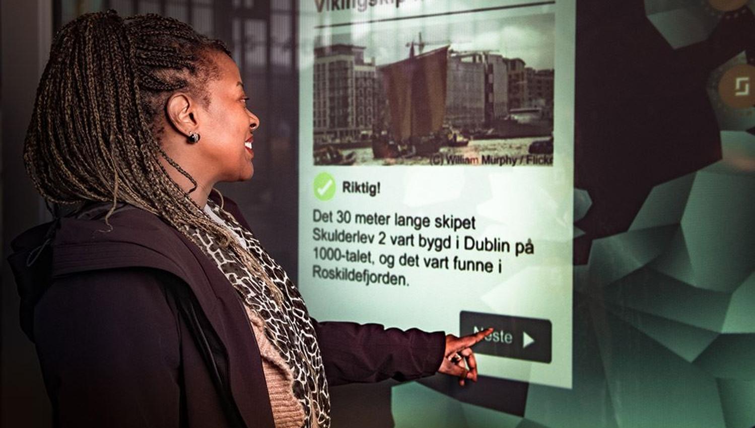 Besøkande brukar informasjonsskjerm for å lære meir om vikingtida.