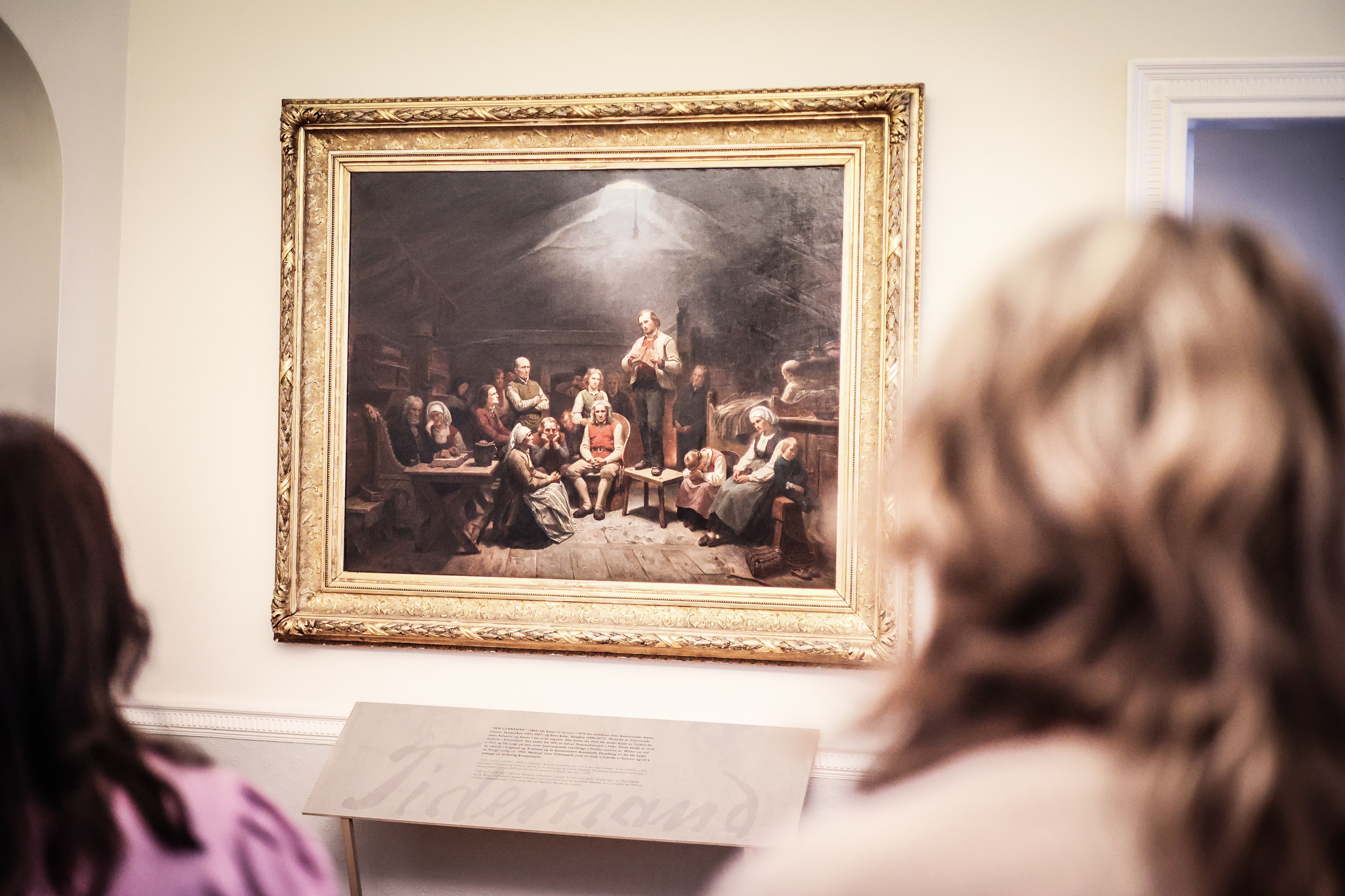 Et par ser på det store maleriet «Haugianerne» på Mandal museum, der Adolph Tidemand skildrer lekpredikanten Hans Nielsen Hauges følgere.