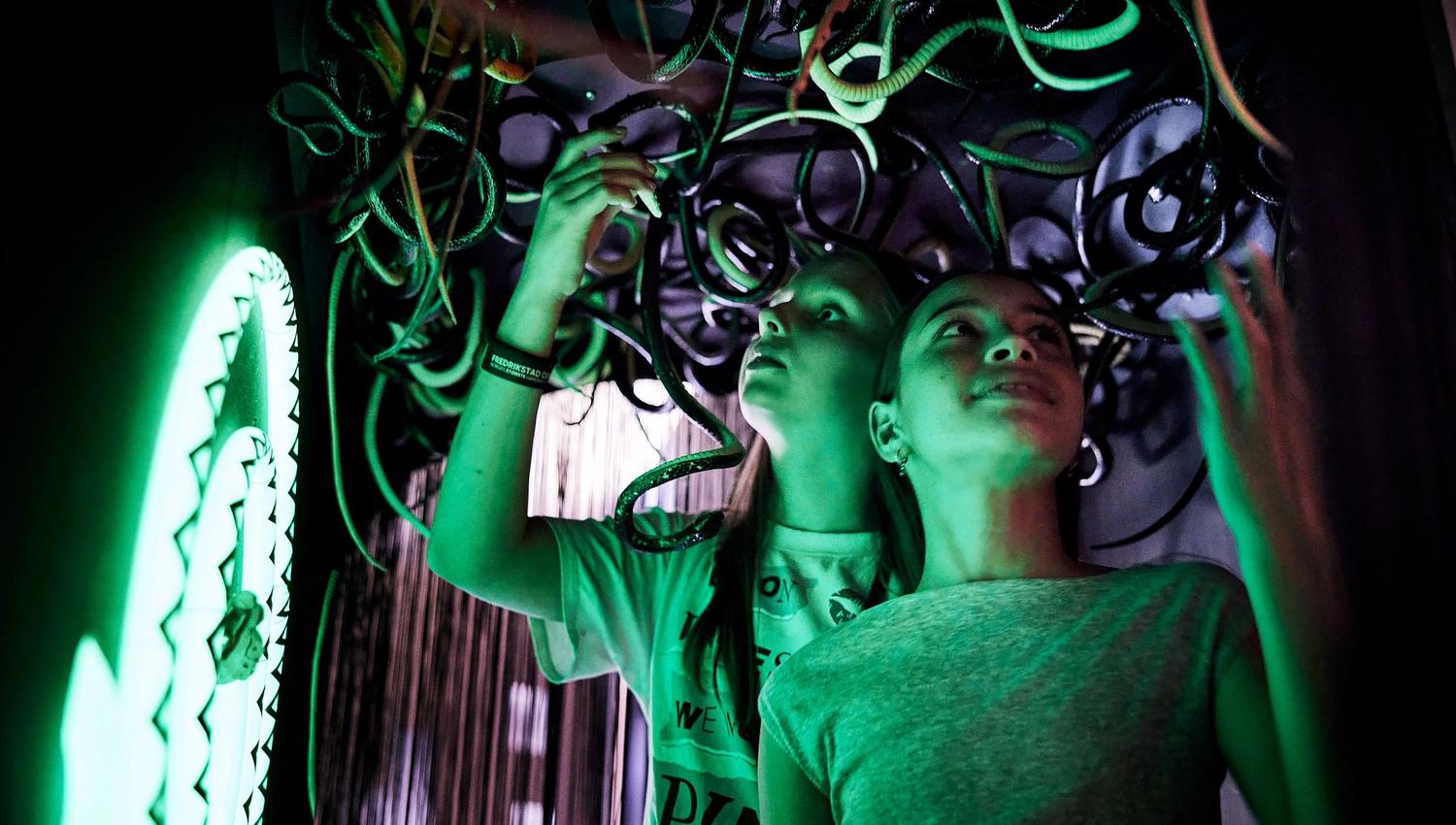 Two children with plastic snakes hanging above their heads