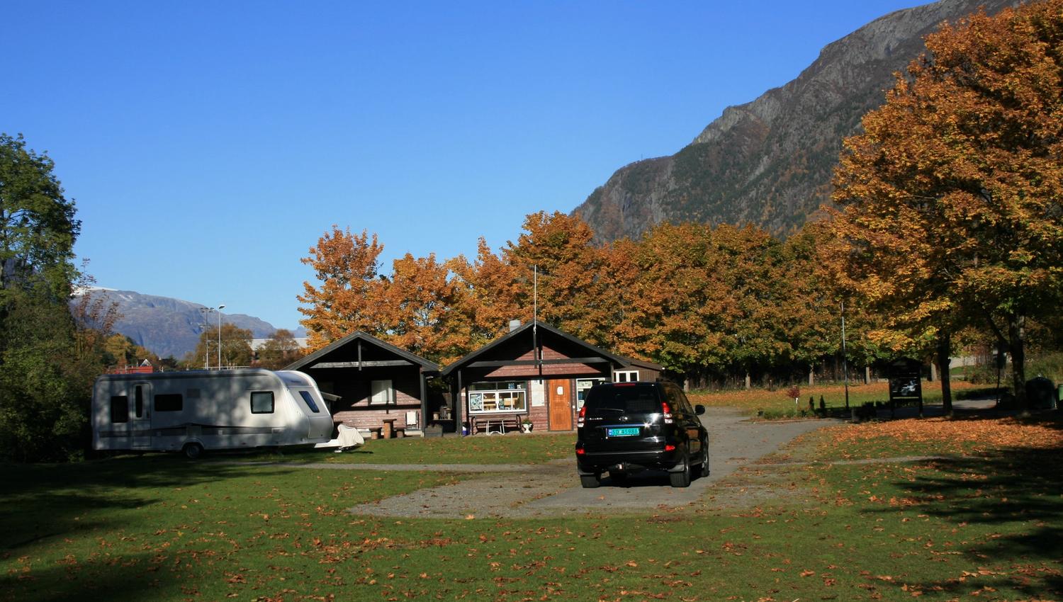 Campingområdet i haustfargar med vogner og hytter mellom trea.