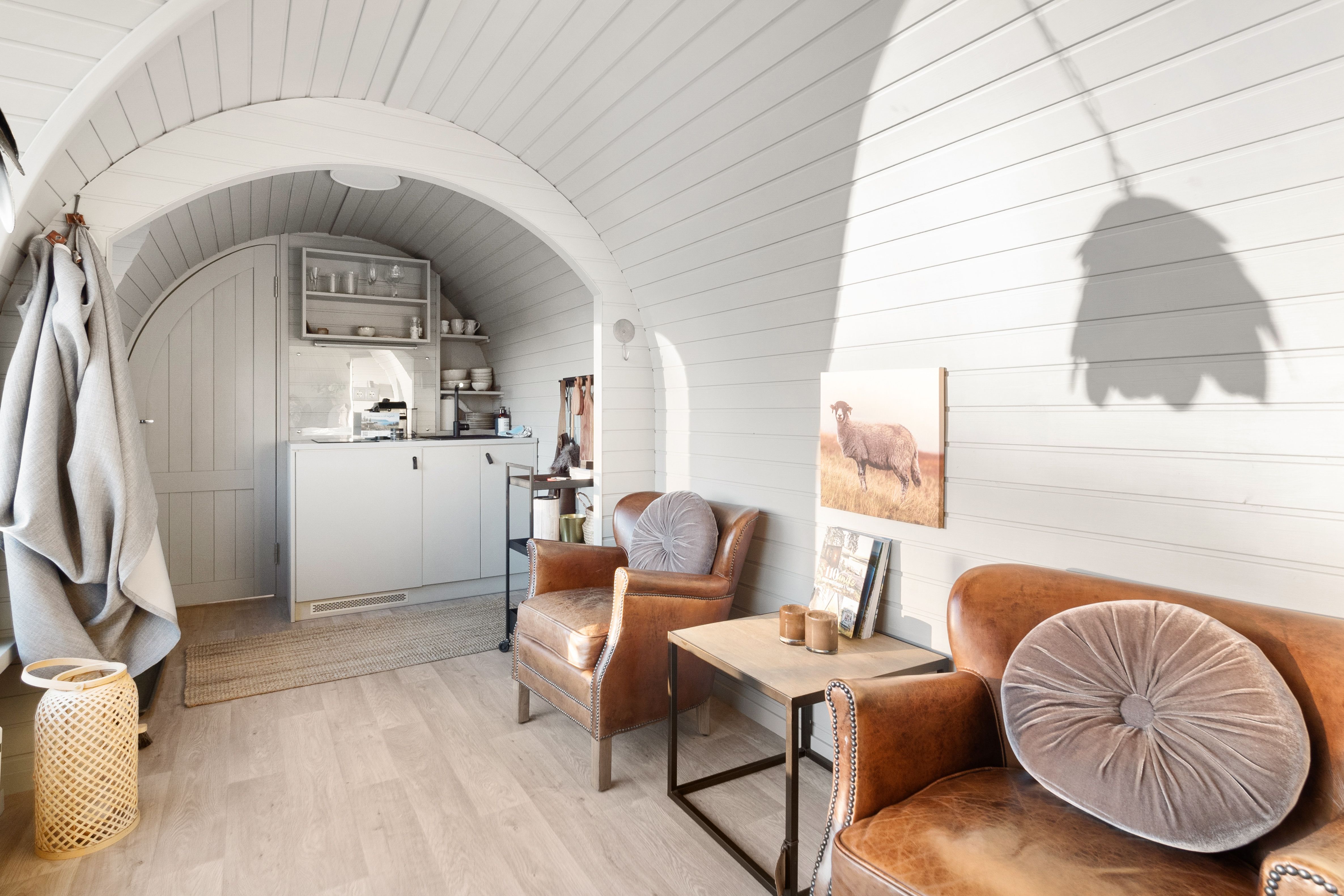 interiørbilde fra en hytte med hvite vegger, stoler og et lite kjøkken