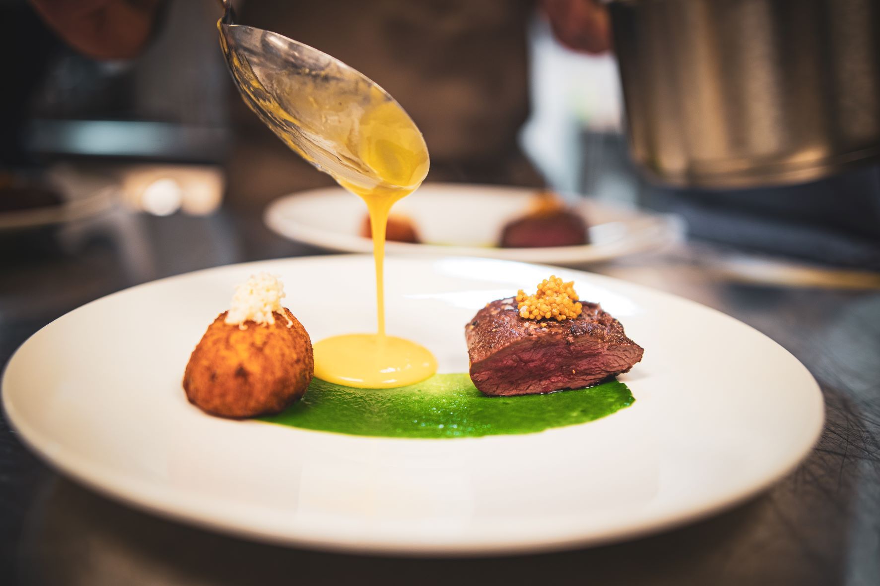 En matrett som en kokk heller saus på fra en skje