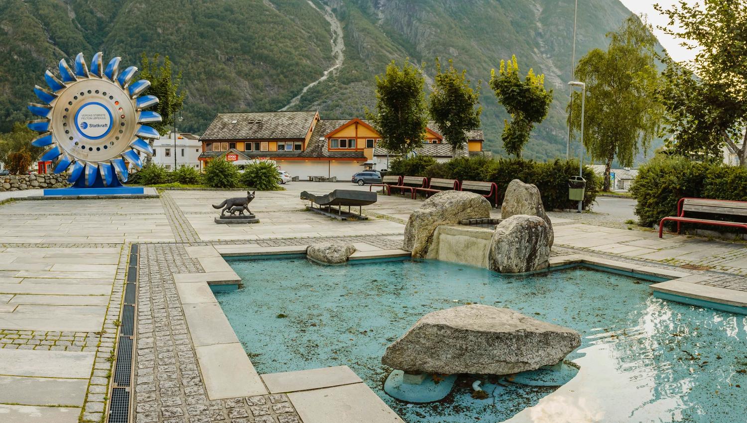 The sculpture park with it's small pool in the middle and the large pelton wheel in the background.