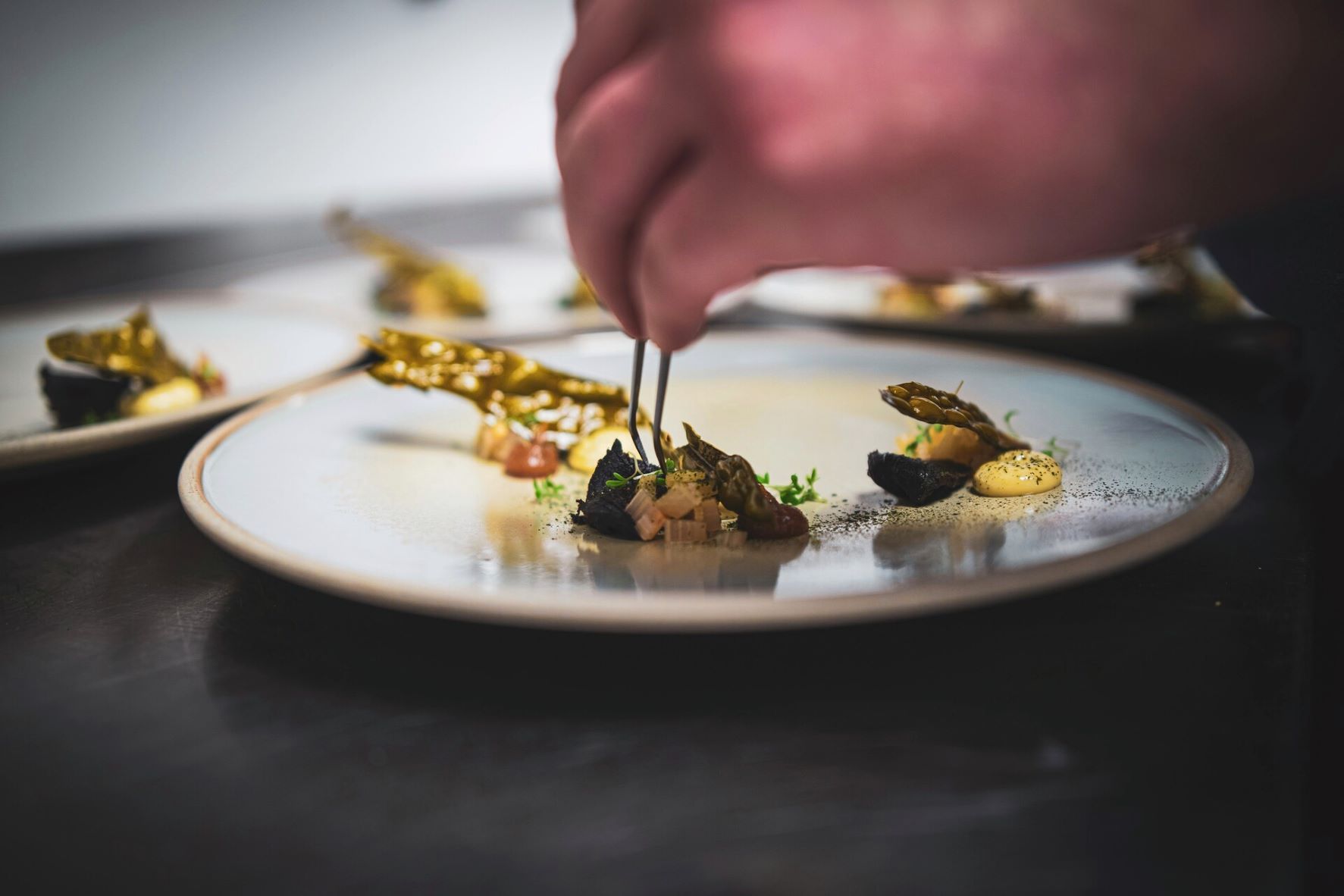 En kokk som forbereder en matrett på en tallerken med pinsett