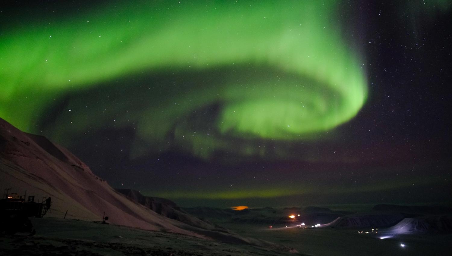 En hvirvel av nordlys på himmelen over en dal