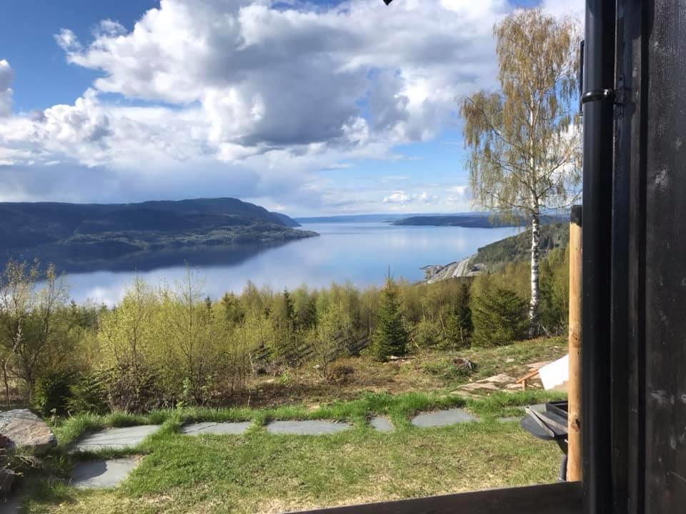 Hageområde med utsikt mot en innsjø og fjell i det fjerne.