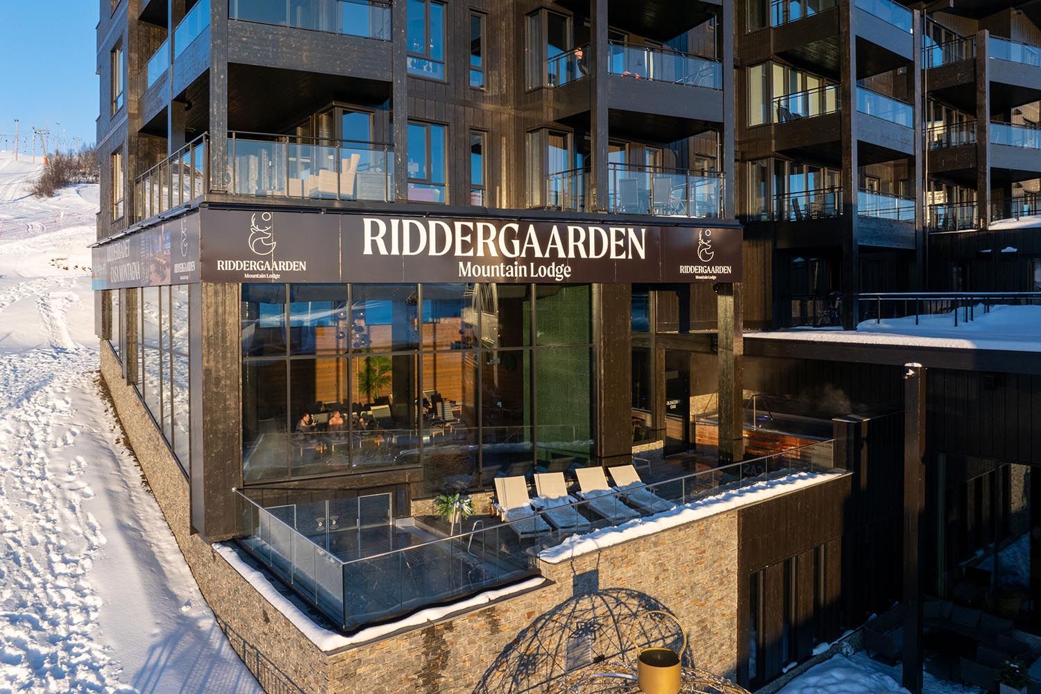 Fasade av leilighetskompleks med svømmebasseng delvis ute på terrasse