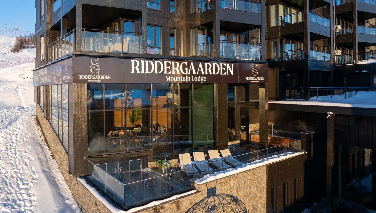 Fasade av leilighetskompleks med svømmebasseng delvis ute på terrasse