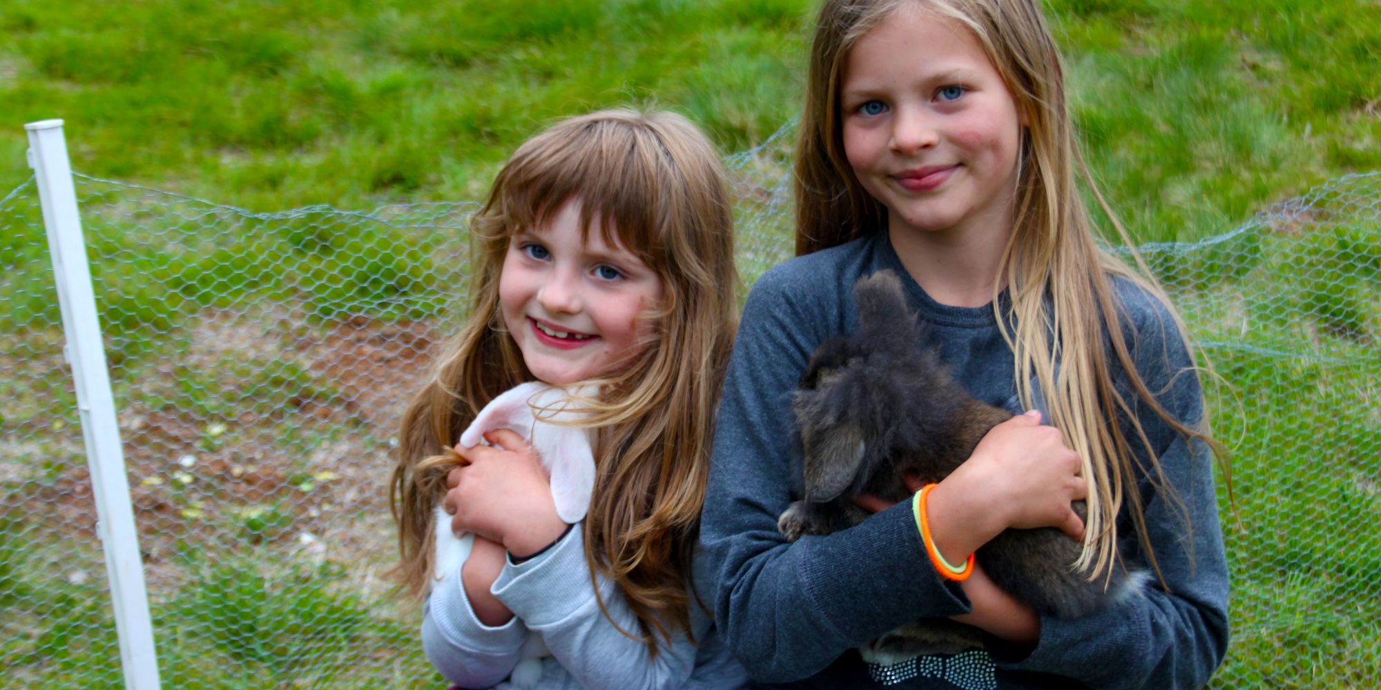 2 fornøyde jenter koser med kaninene på Holsingseteren