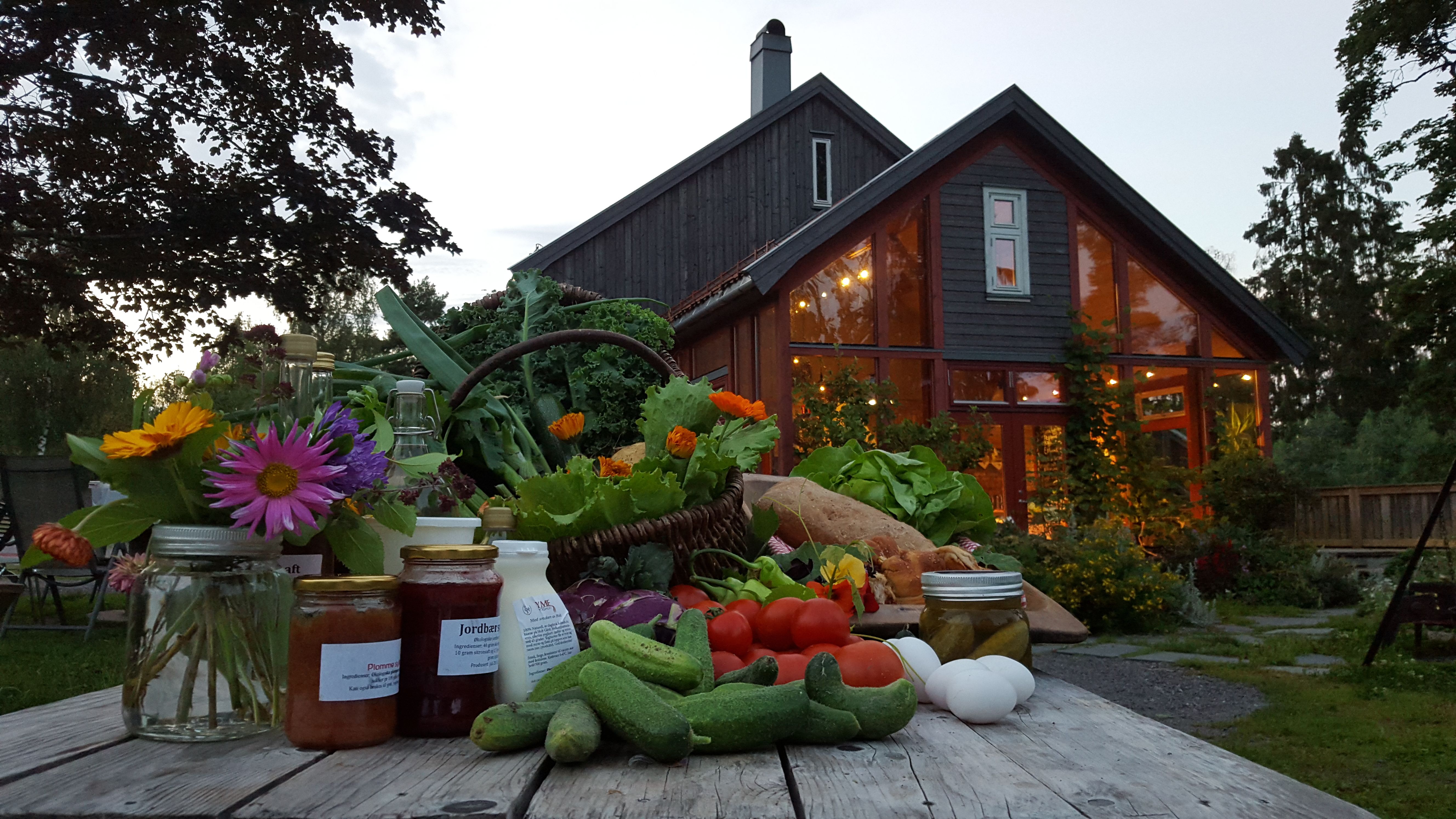 Farmhouse with brewery in the background, and organic vegetables and goods on a table in front