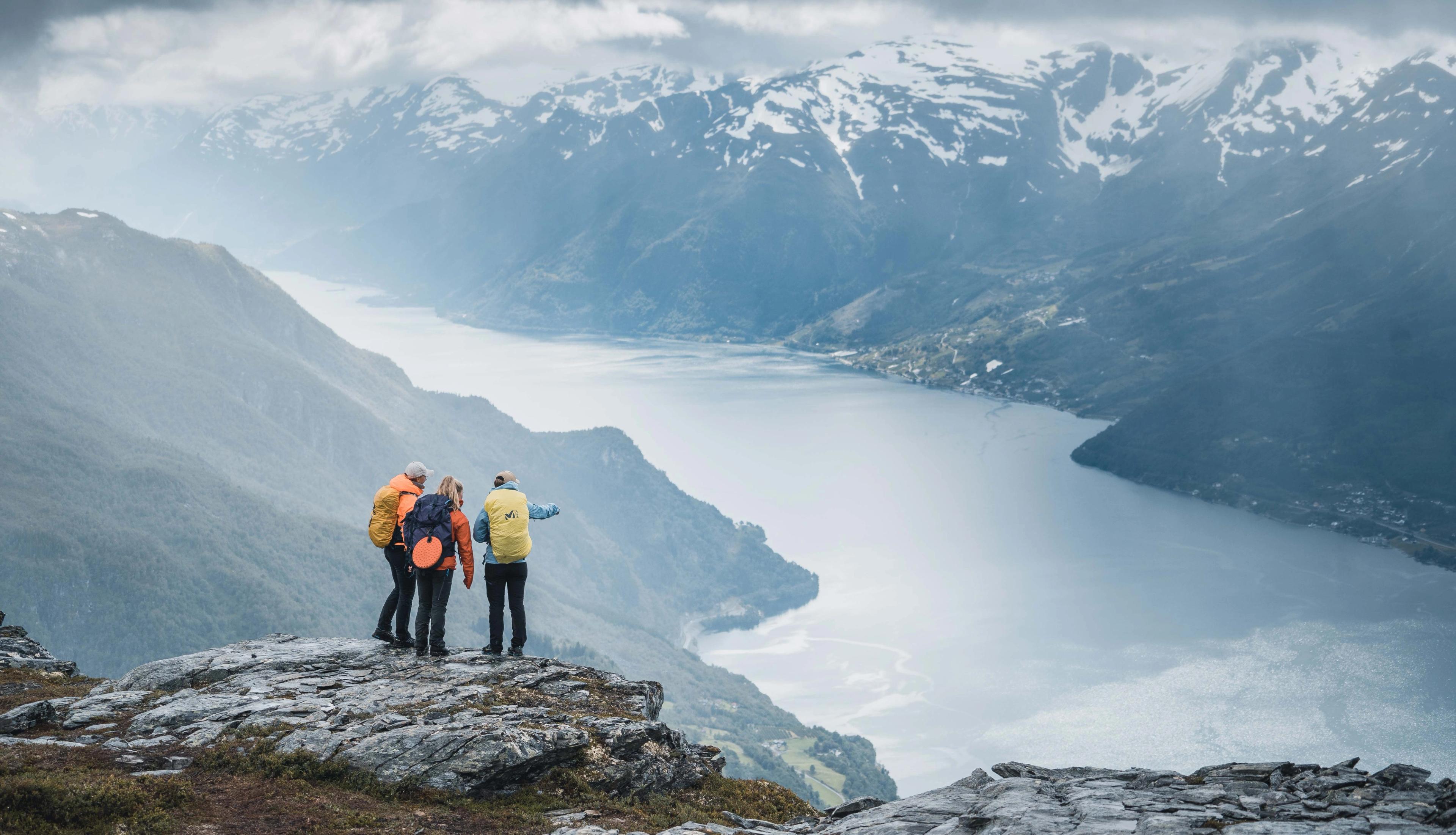 Drei Wanderer auf dem Gipfel des Dronningstien mit einem herrlichen Blick auf den Sørfjord und den Folgefonna-Gletscher im Hintergrund.
