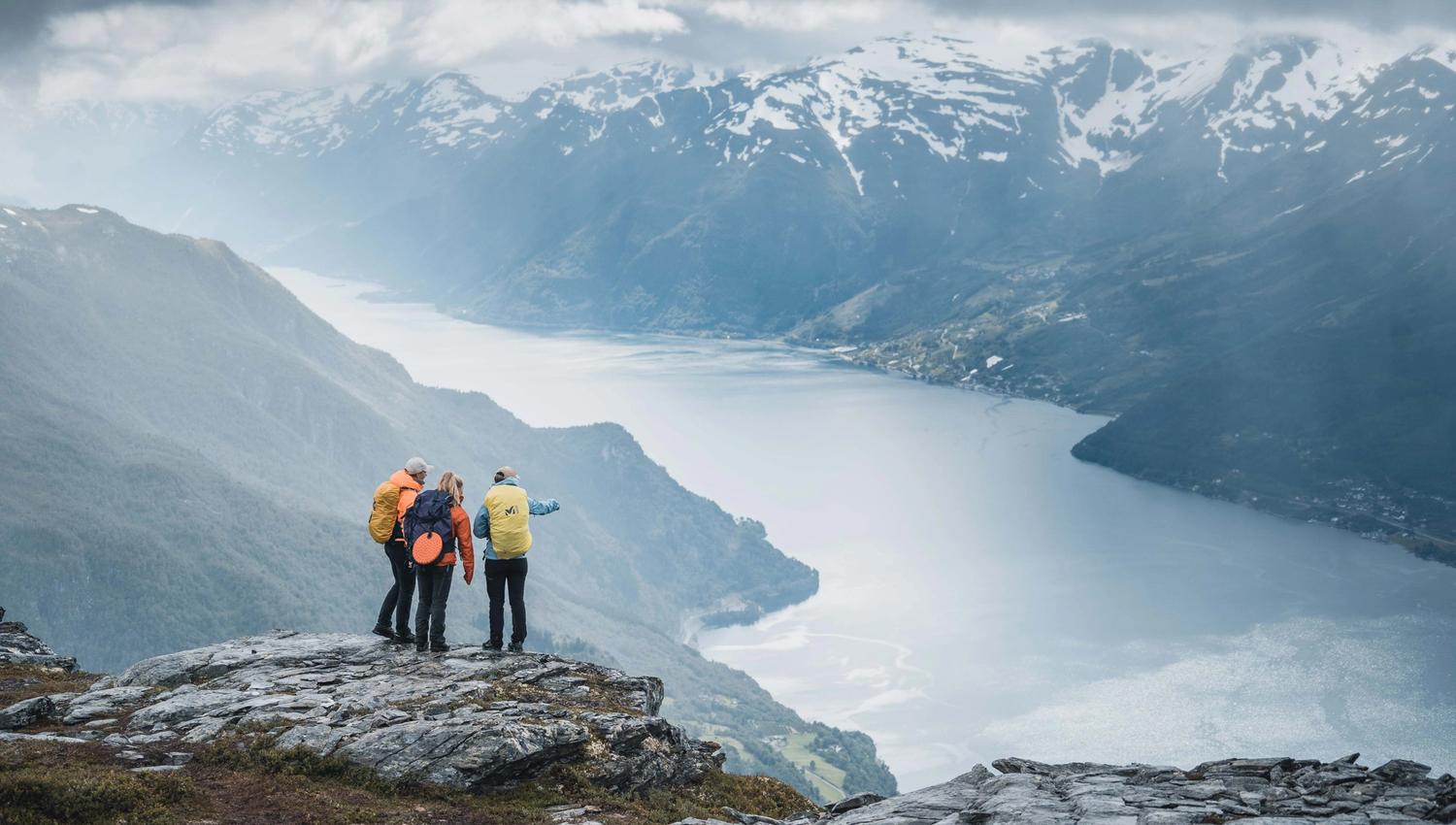 Three hikers at the top of Dronningstien, enjoying a stunning view of Sørfjorden and Folgefonna glacier in the background.