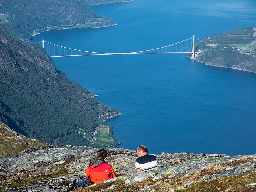 To personar kviler på fjellet med utsikt mot ei fjordbru i Hardanger.