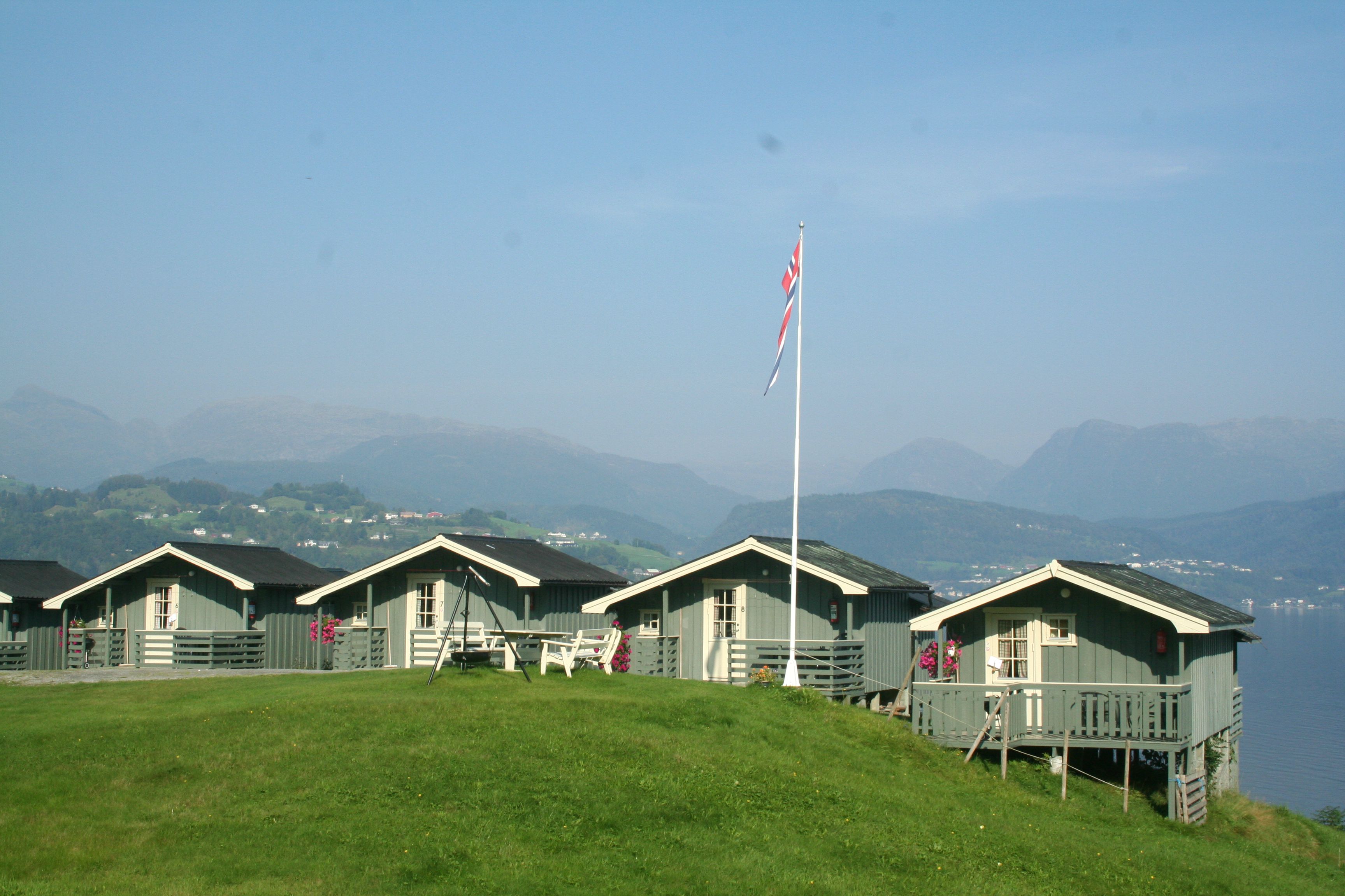 Rader med hytter på Oddland Camping med panoramautsikt mot fjorden og fjella i Hardanger.