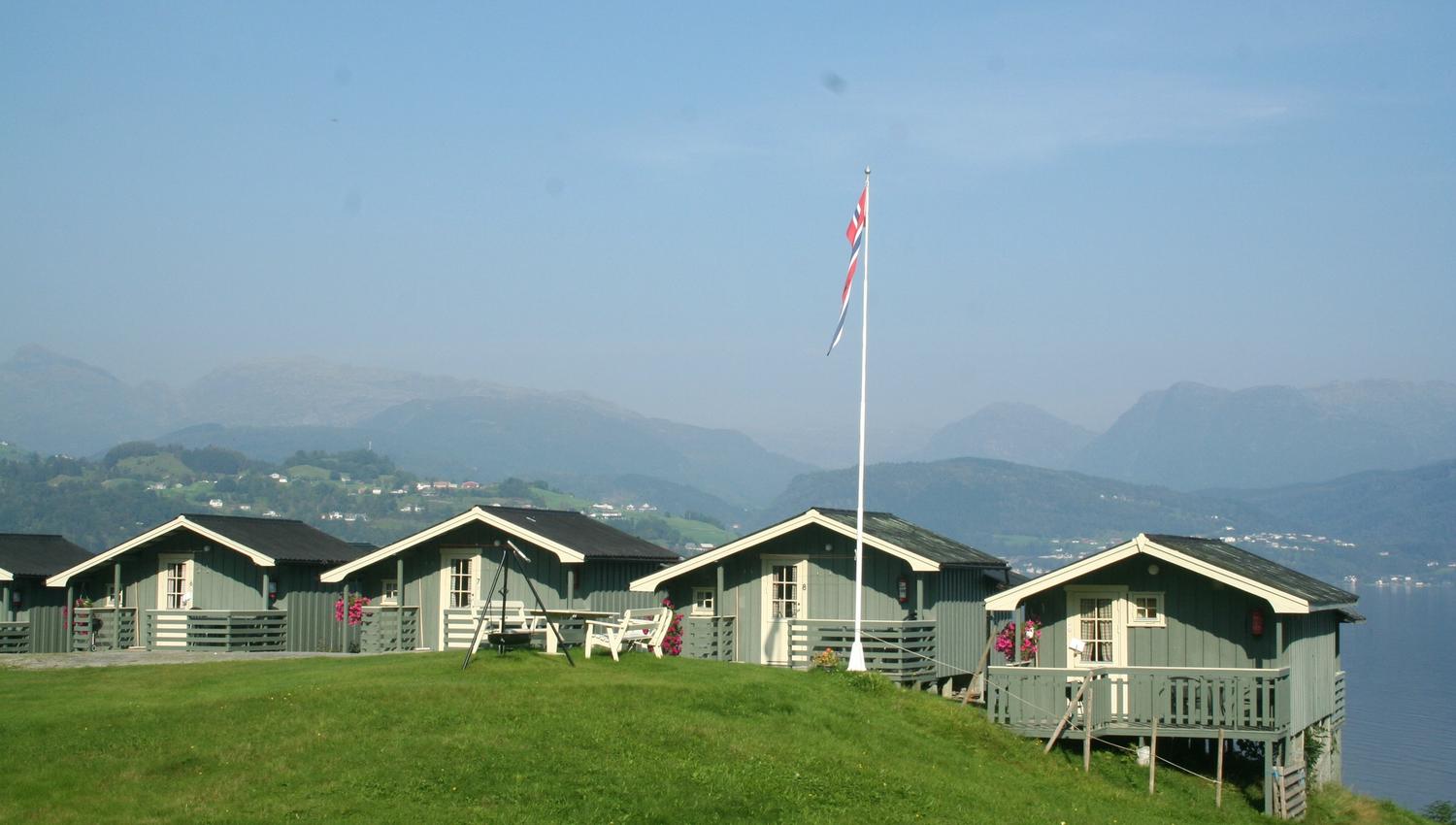 Rader med hytter på Oddland Camping med panoramautsikt mot fjorden og fjella i Hardanger.