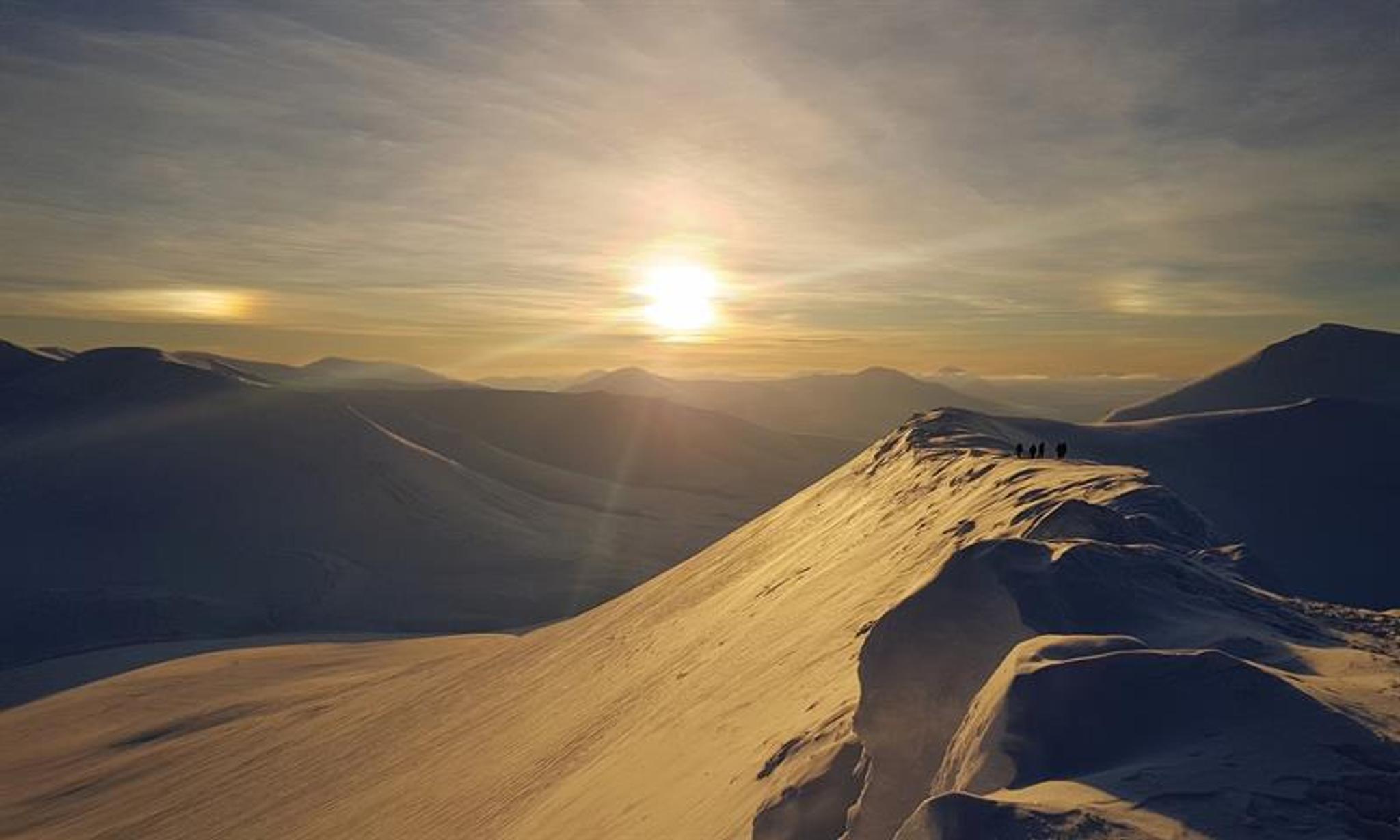 The sun shines on the snow-covered mountain top with beautiful snow-covered mountains in the back ground