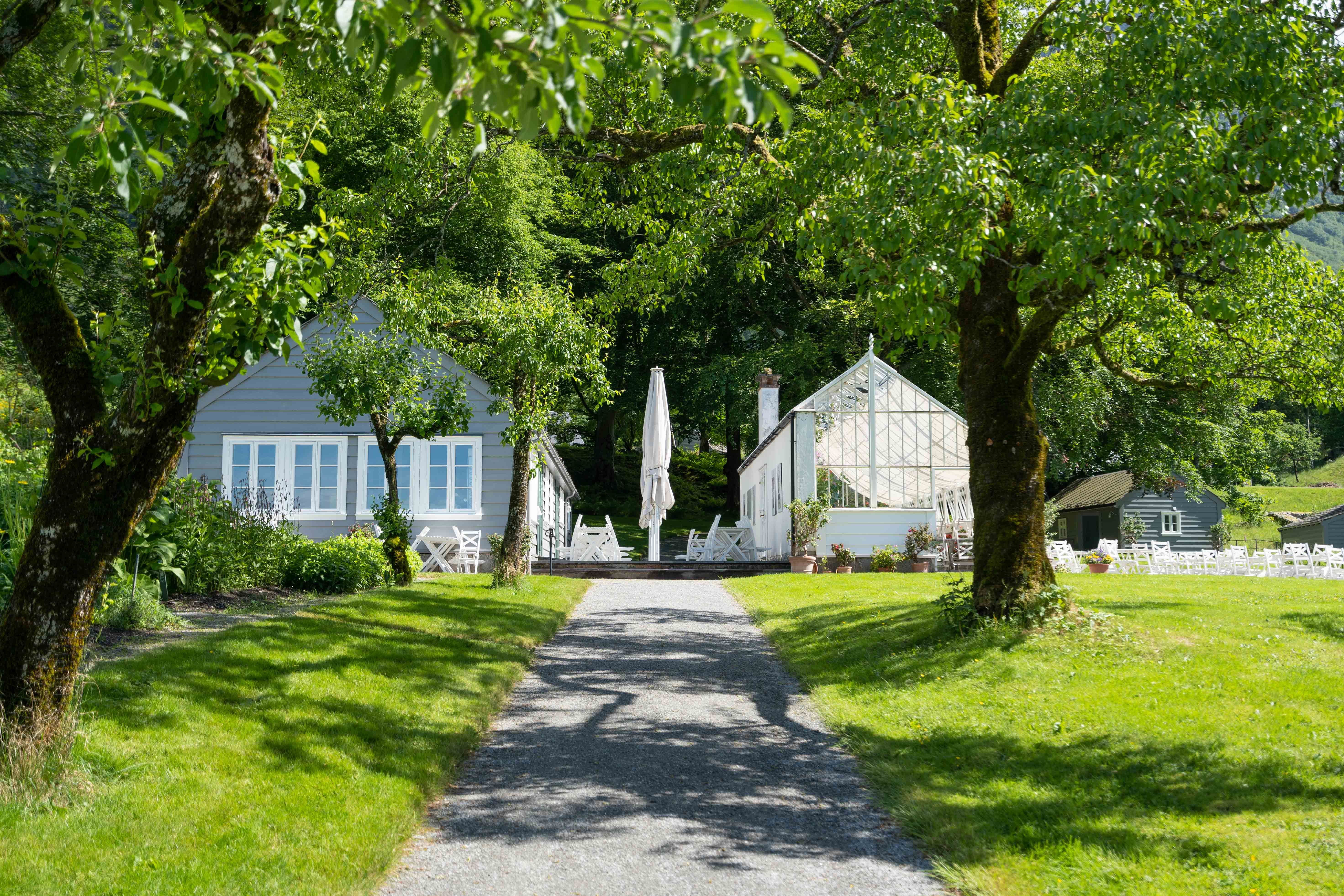 Stien som fører mot veksthuset og kafeen ved Baroniet i Rosendal, omkransa av grøn natur.