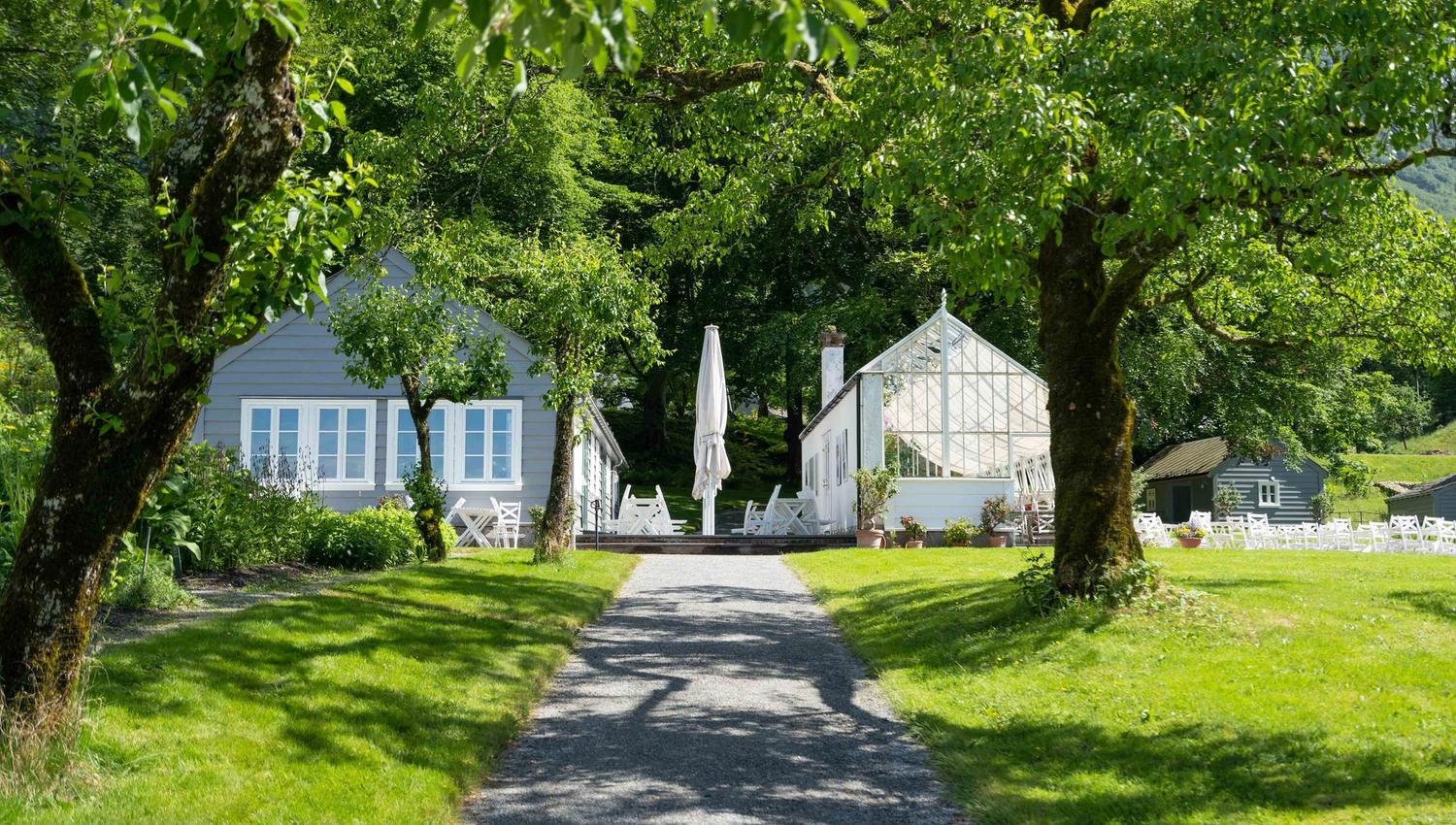 Stien som fører mot veksthuset og kafeen ved Baroniet i Rosendal, omkransa av grøn natur.