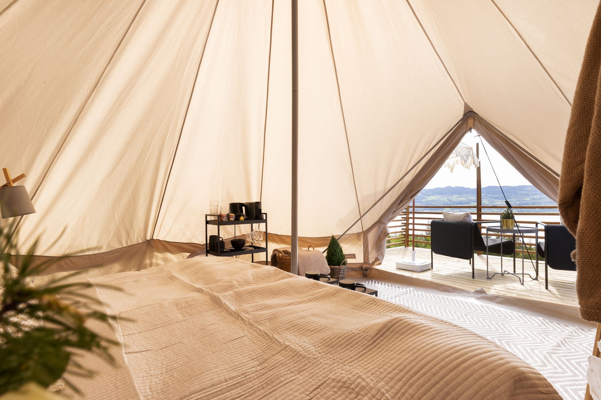 Oversiktsbilde inne i teltet med seng, bord og utsikt.