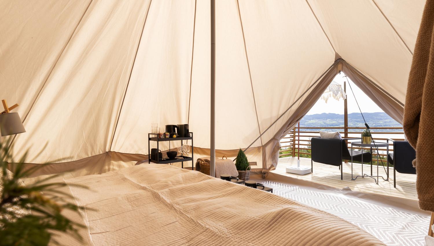 Oversiktsbilde inne i teltet med seng, bord og utsikt.