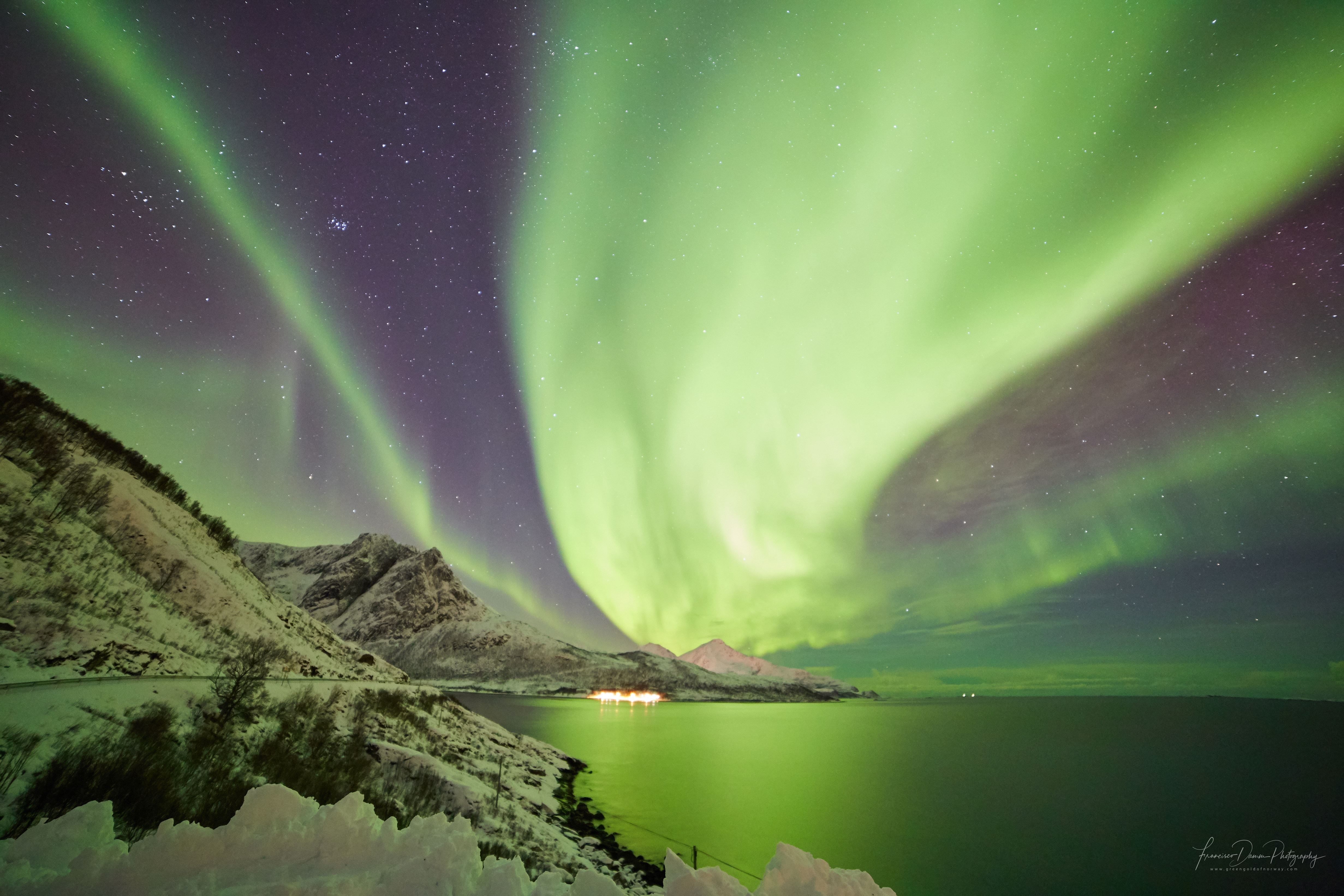 sterkt nordlys på himmelen over fjell og havet