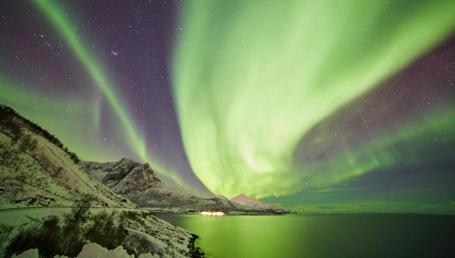 sterkt nordlys på himmelen over fjell og havet