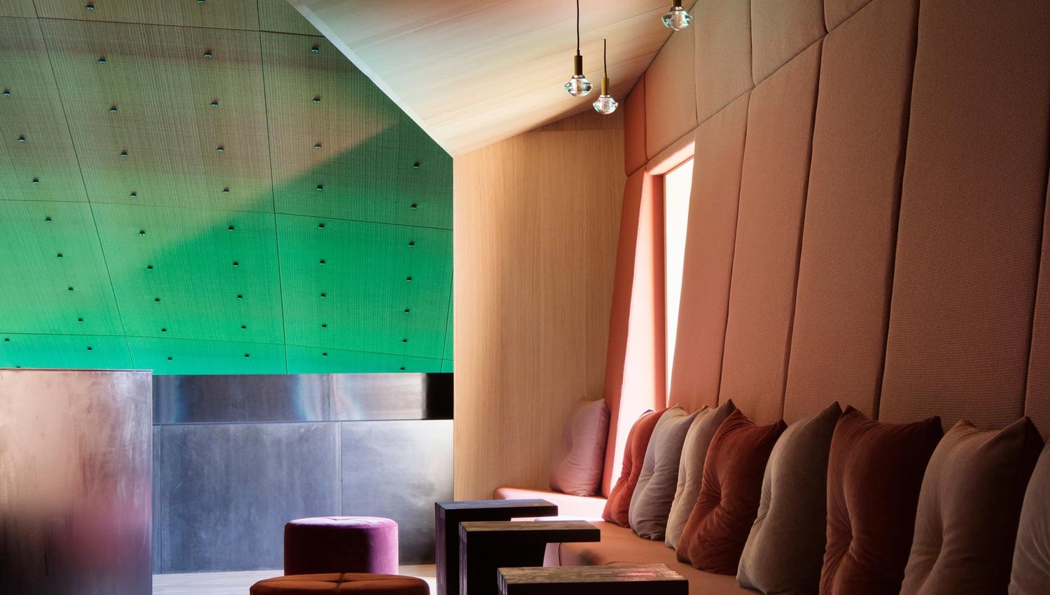 Sofa with small tables between the seats. Green lighting on the ceiling, cozy atmosphere.