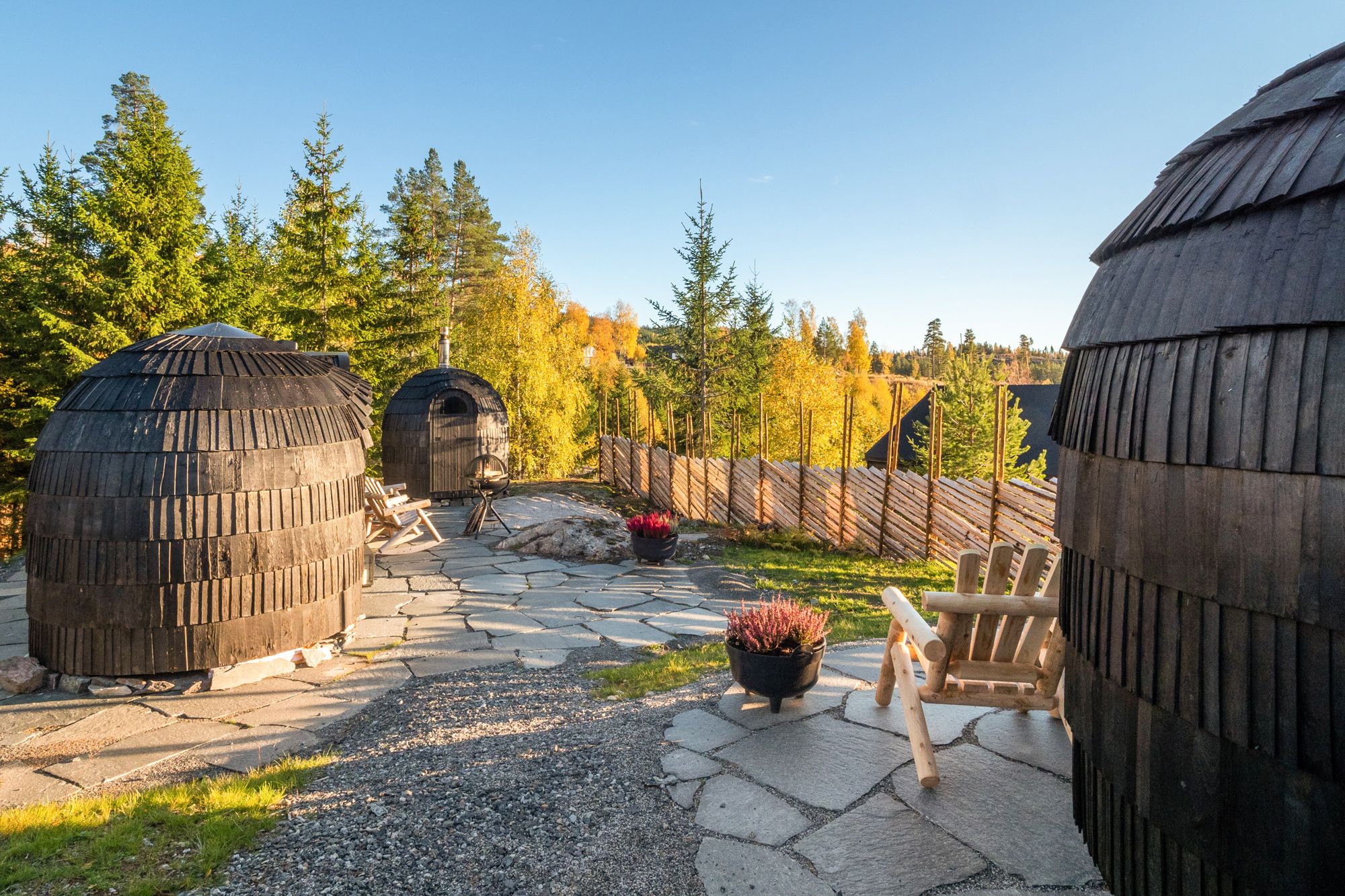 3 småhytter som ser ut som kongler med gjerde og skog rundt