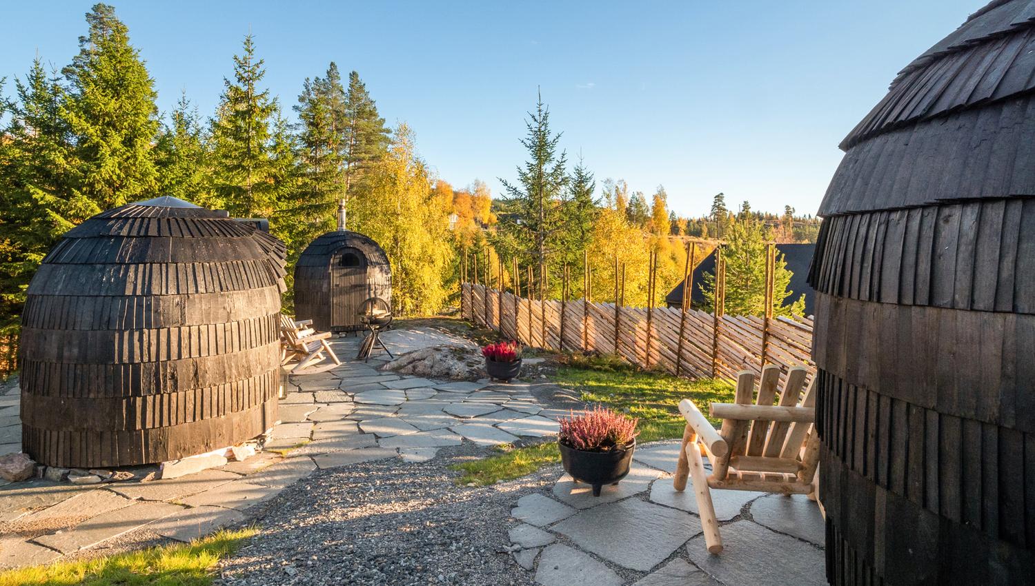 3 småhytter som ser ut som kongler med gjerde og skog rundt