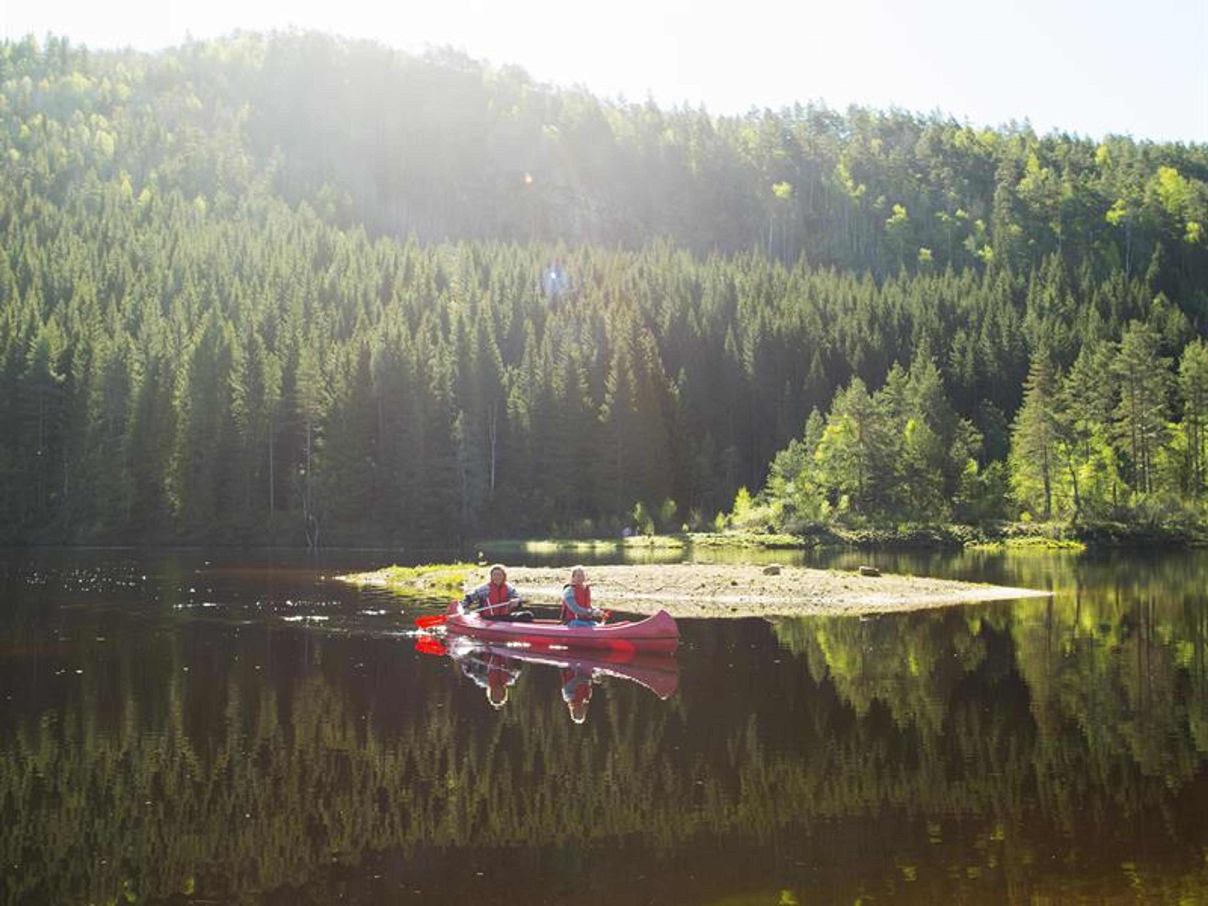 To personer i en rød kano som padler på vannet