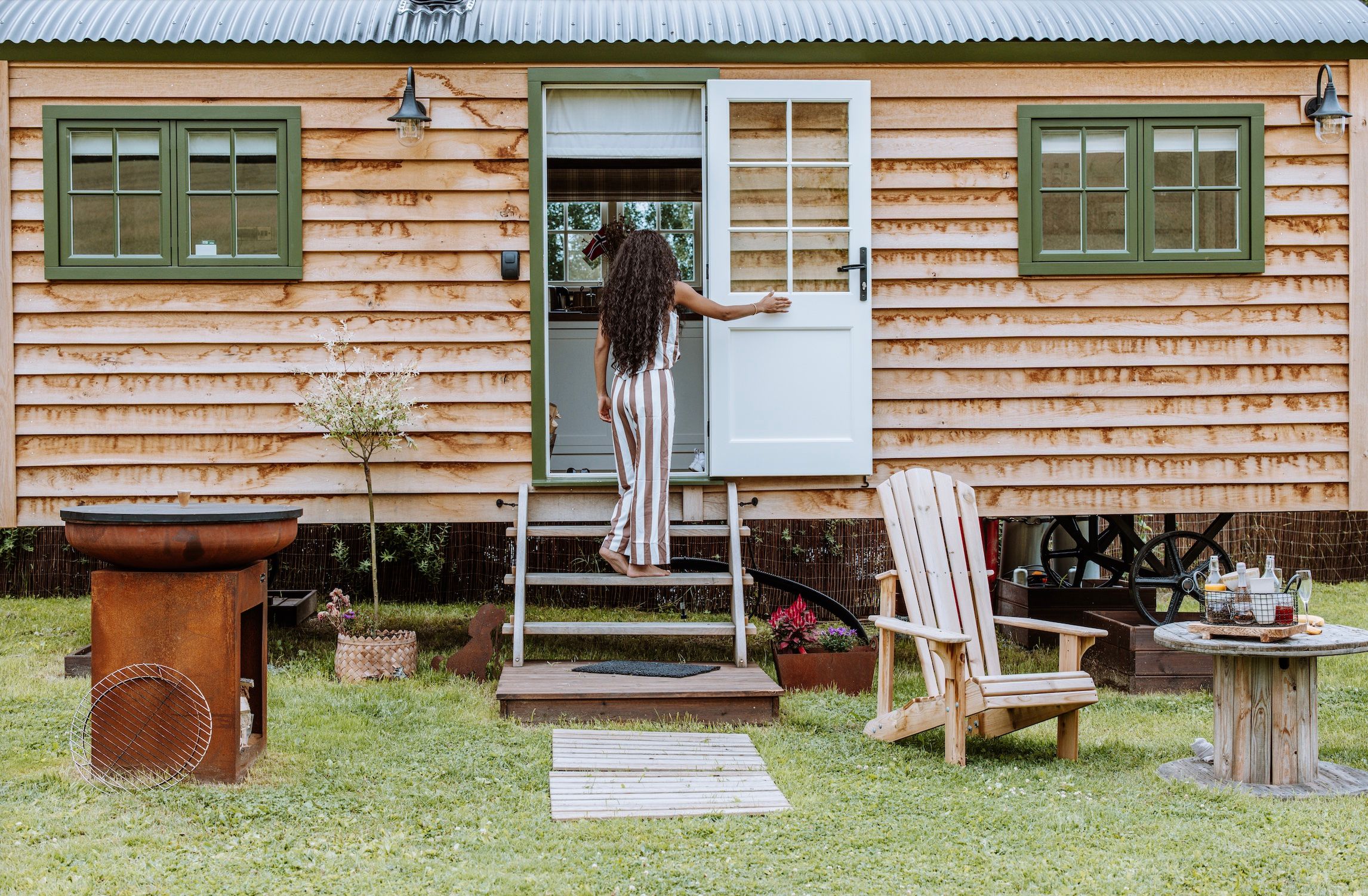 Par foran Shepherds Hut - lite trehus med grønne vinduer og stoler foran