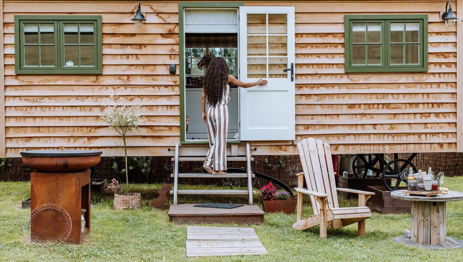 Par foran Shepherds Hut - lite trehus med grønne vinduer og stoler foran